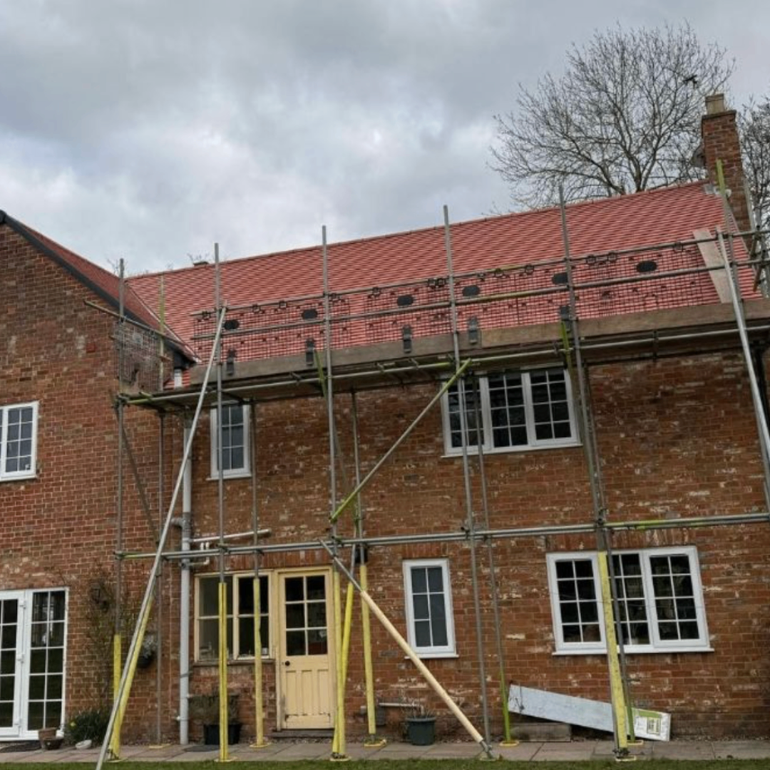 Completed re-roofing project on a brick home with scaffold in place